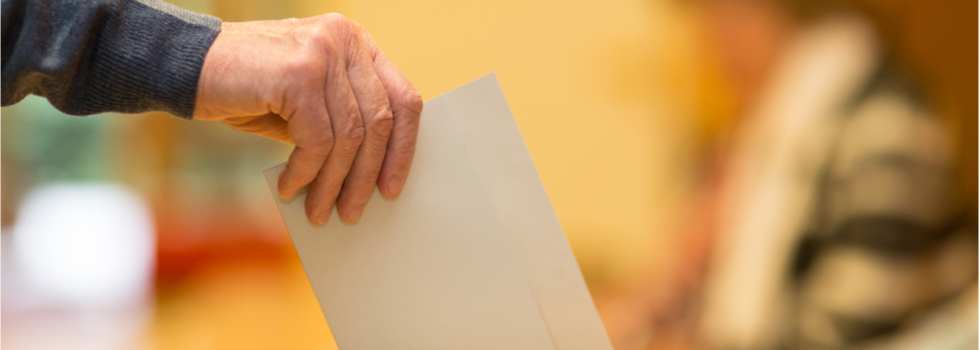 A man putting a ballot paper into a ballot box.