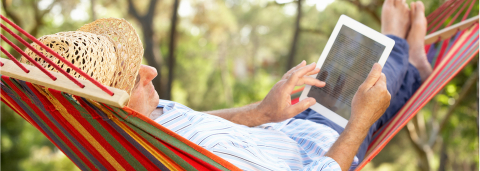 A man in a hammock using a tablet.