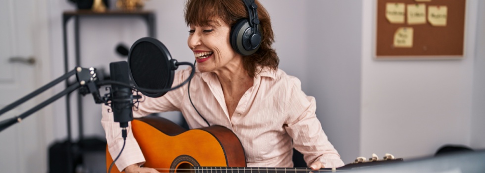 A woman playing a guitar in a music studio.