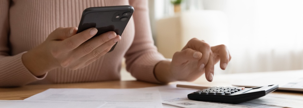 A woman using a phone and calculator.