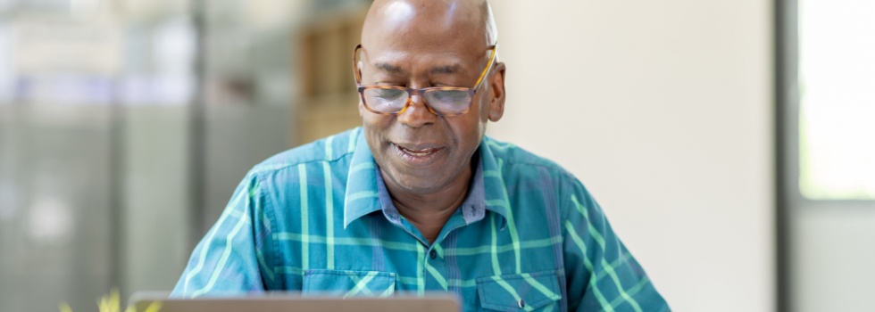 A man reviewing paperwork at his computer.