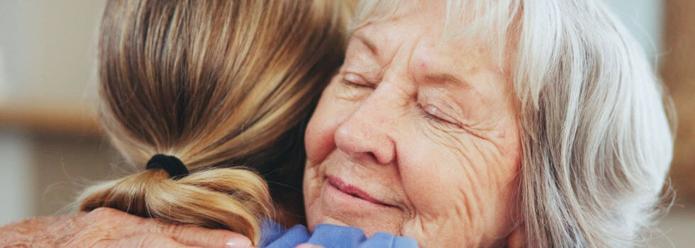 A senior woman hugging a caregiver.
