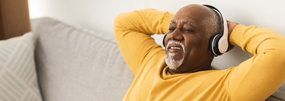A man relaxing on a sofa with his hands behind his head.