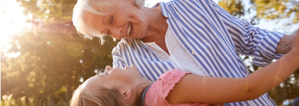 A grandmother playing with her granddaughter outside.