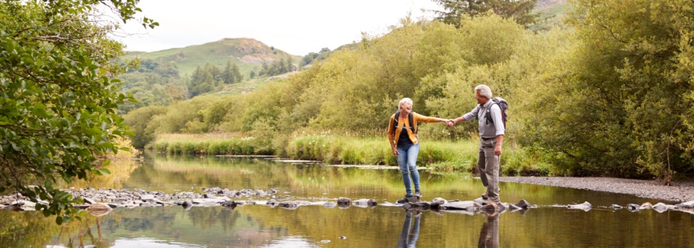 A couple walking across stepping stones.