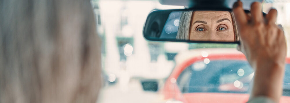 A driver adjusting the rear view mirror in a car.