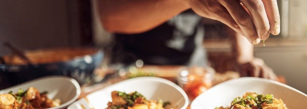 A man adding garnishes to a meal.