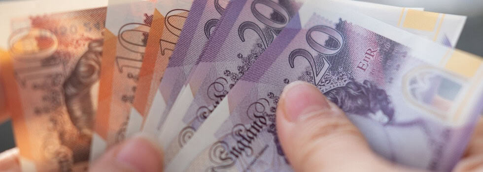 A person holding UK bank notes.