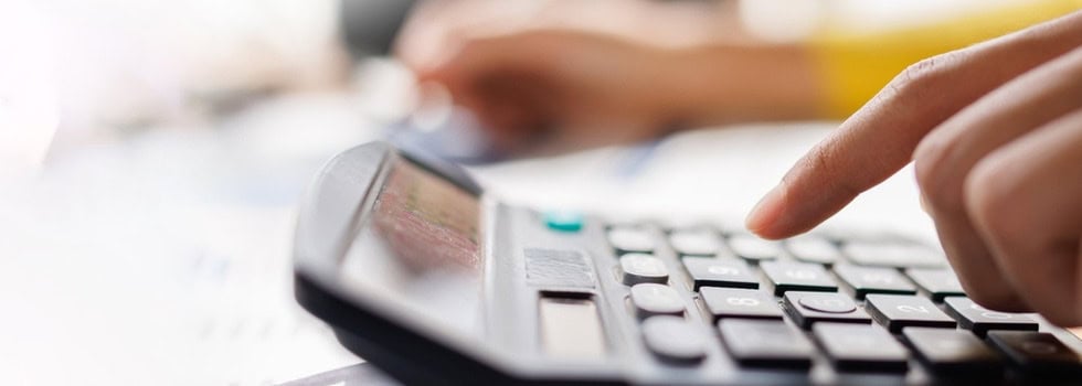 A person using a calculator while reviewing paperwork.