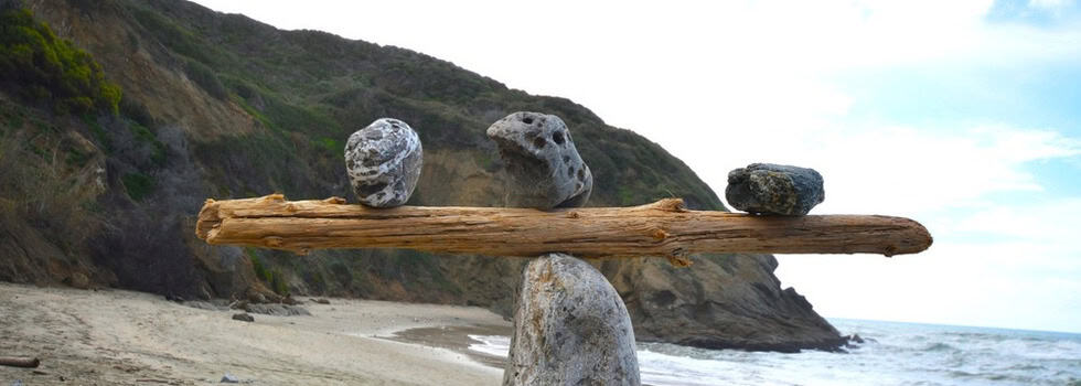Rocks balancing on log on top of another rock