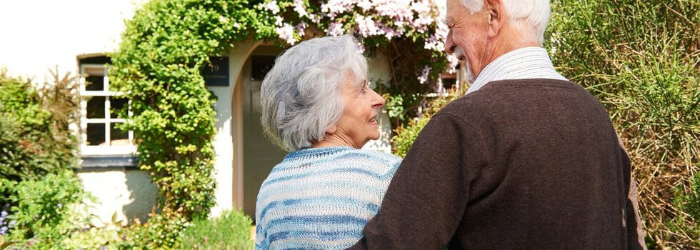 Rear view of senior couple outside pretty cottage